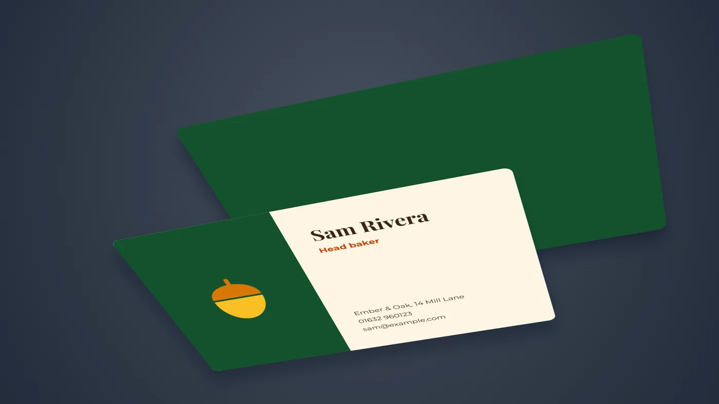 Two business cards lying on a navy surface in perspective: the front with the acorn logo, Sam Rivera, Head baker and the café's address, and a green back card behind it