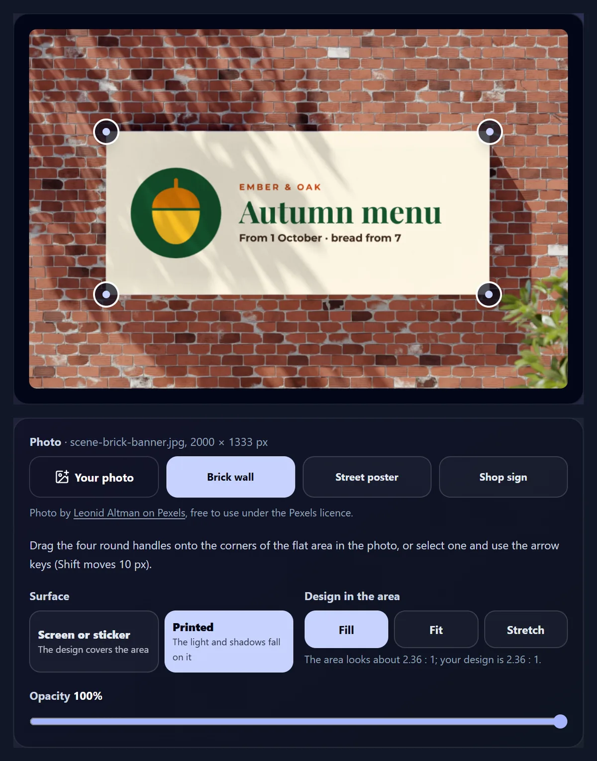 The tool on a photo: a white banner on a brick wall with leaf shadows, now showing the Ember & Oak autumn menu banner, with four round handles on its corners, and below the photo choices, Surface: Printed, Design in the area: Fill, the area about 2.36 : 1 and the design 2.36 : 1, and Opacity 100%